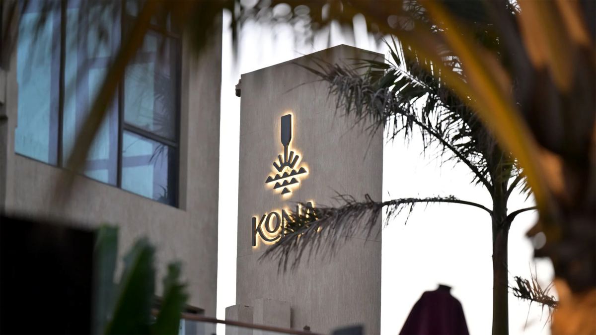 Illuminated logo on the stone entrance tower of Kona Marine Sport Club, framed by palm fronds