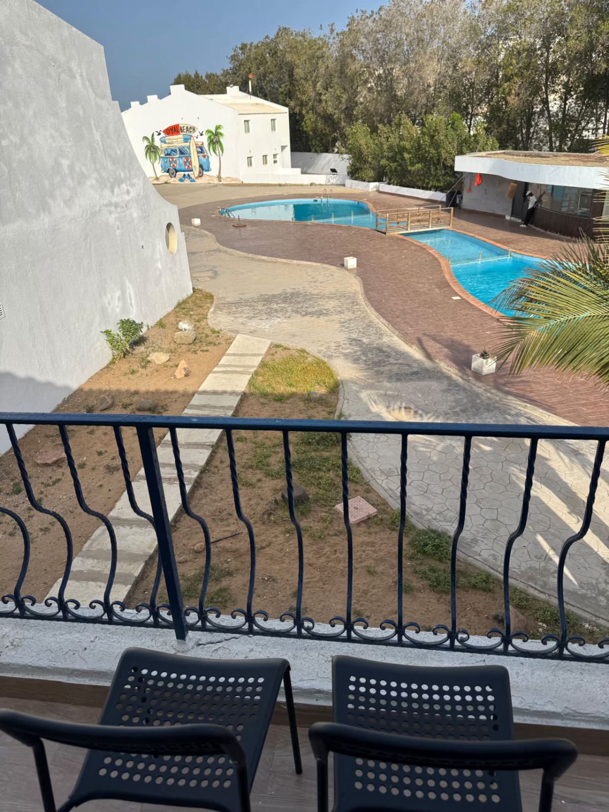 Balcony view over Siyal Resort’s twin pools, wooden footbridge and Siyal Beach mural
